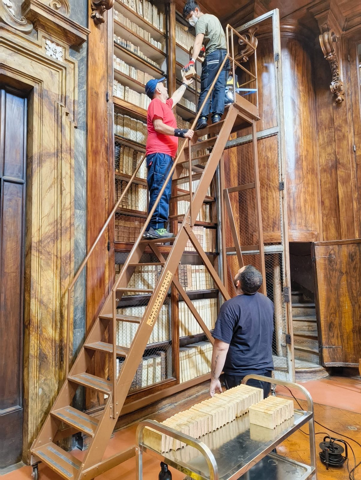 Depolveratura manuale di volumi antichi su scaffalatura storica